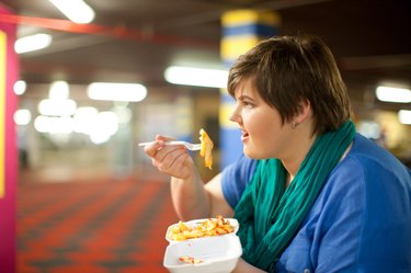 Young woman eating takeaway fries