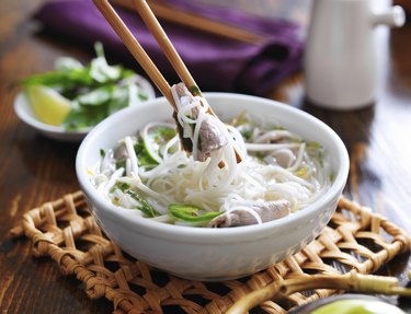 a bowl of pho with noodles and beef