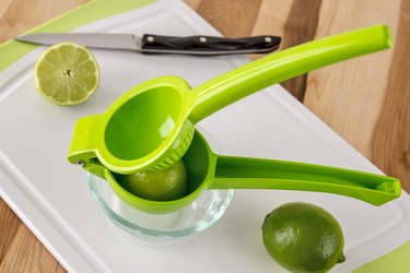 Cut limes with juicer and knife on cutting board
