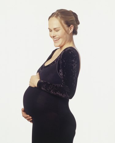 Pregnant woman touching stomach, smiling