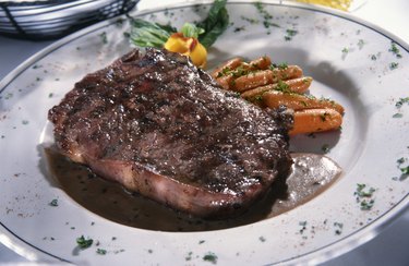 Red meat on a dinner plate with baby carrots.