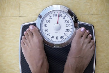 Low section view of a woman standing on a weighing scale