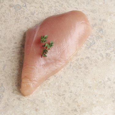Raw chicken breast with parsley garnish