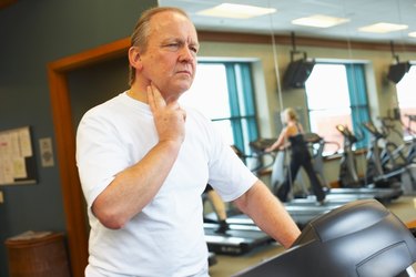 Man checking his pulse on treadmill at gym