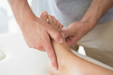 Physiotherapist massaging patients foot