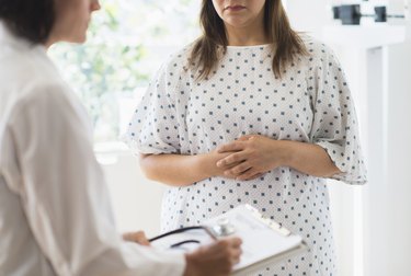 person wearing a surgical gown and talking to a doctor in her office about what temperature body fat melts at