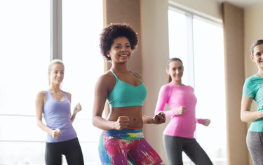 group of smiling people dancing in gym or studio