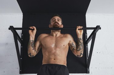 Tattooed male athlete performs a pullup variation called an inverted row.