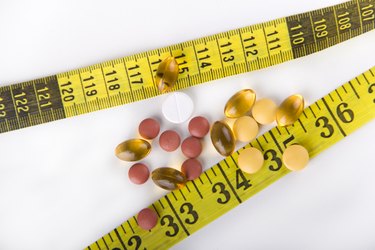 Diet Pills with yellow measuring tape