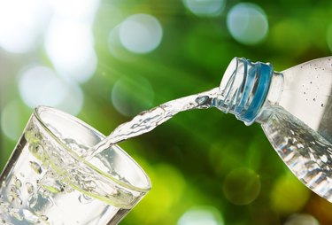 Drinking water is poured from a bottle into a glass