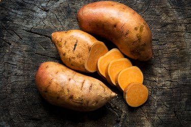 Raw sweet potatoes on wooden background closeup