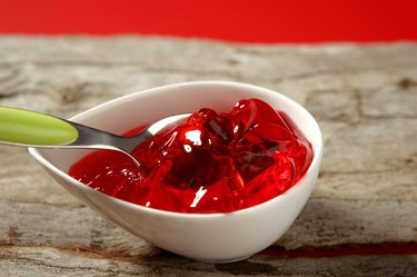 white bowl of red jello with a green spoon sticking out