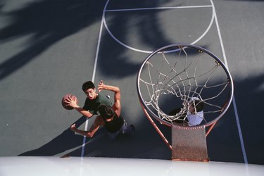 Three teenage boys (16-17) playing basketball, elevated view