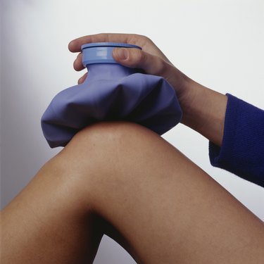 Woman applying ice pack to knee, (Close-up)