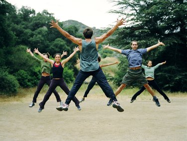 Man leading group of people in boot camp exercises, rear view