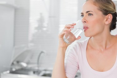 Pensive blond woman drinking water