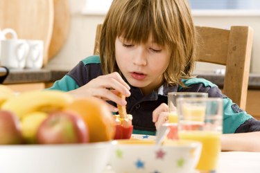 Boy dipping a piece of toast into a boiled egg