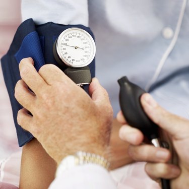 Close-up of a pair of human hands checking the blood pressure of a patient