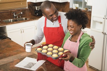 African American couple holding tray of muffins