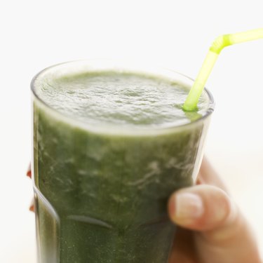 Person holding a glass of thick green vegetable juice