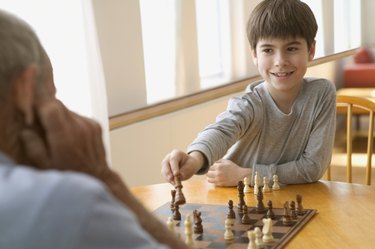 Boy playing chess with elderly man