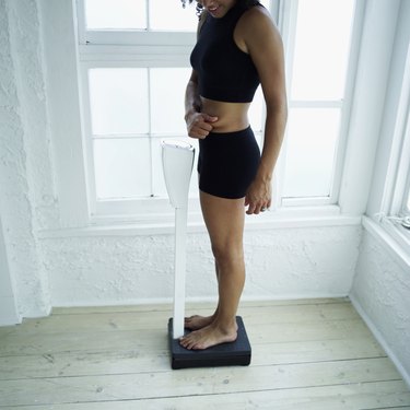 Young woman standing on a weighing scale