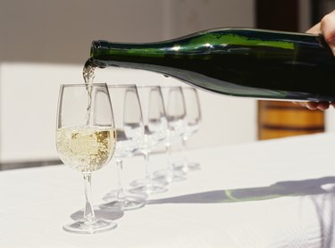 person pouring white wine into a wineglass