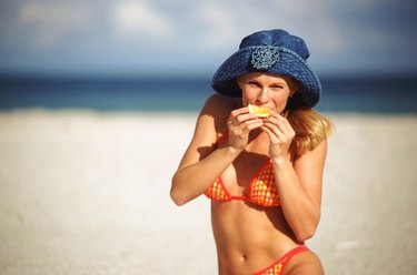 Young woman eating orange on beach