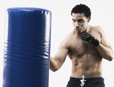 Mixed Race man using punching bag