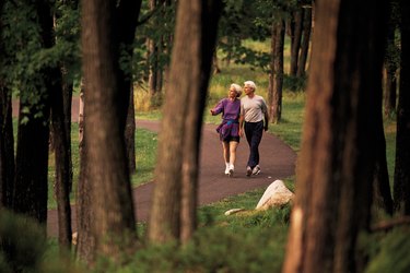 Mature couple walking on trail through forest