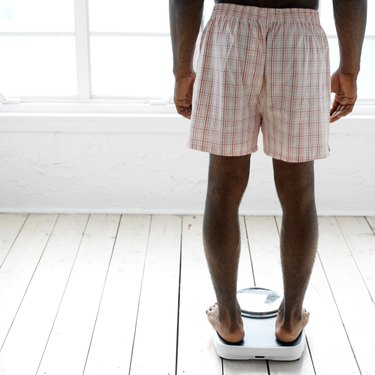 behind of a young man weighing himself on a scale