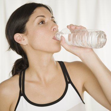 Hispanic woman in athletic gear drinking bottle of water