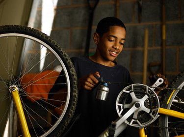 Teenager oiling bicycle chain