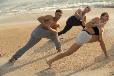 Group of people performing yoga on the beach