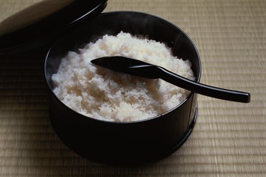 Cooked rice in bowl with scoop, high angle view