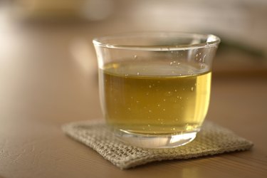 Glass of green tea on coaster, close-up