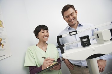 Man standing on weighing scales beside nurse in hospital