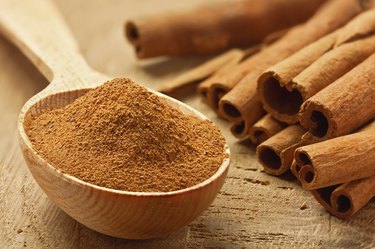 Cinnamon sticks and powder on wooden table.