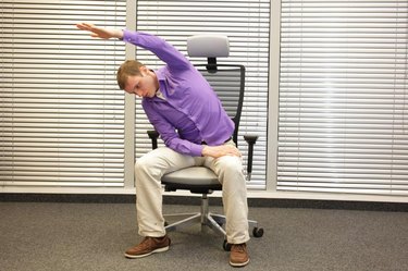 man exercising on chair in office, healthy lifestyle - front view