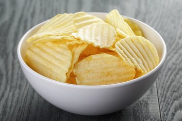 rippled organic chips in white bowl on wooden table