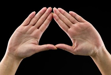 Real people, caucasian woman's hands on black background forming a triangle. In some countries this is a feminist hand sign   (this picture have been shot with a Hasselblad HD3 II 31 megapixels)