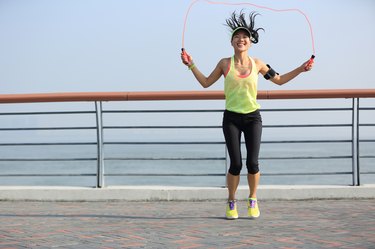 young fitness woman jumping rope at  seaside