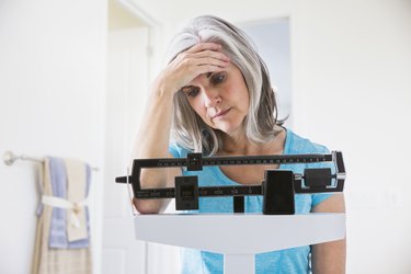 Unhappy Caucasian woman standing on weight scale