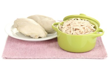 Shredded boiled chicken in green pan isolated on white