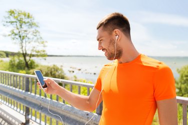 smiling young man with smartphone and earphones