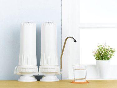 Water filters that remove sodium on a countertop with a glass of water