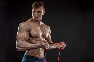 A young athletic man exercising and with a chest expander,  or resistance band.
