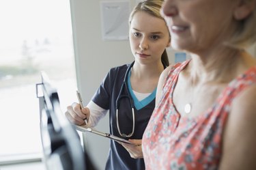Nurse noting patients weight on scale in clinic