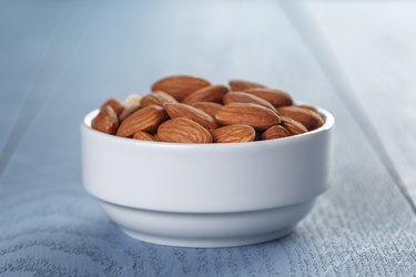 roasted almonds in white bowl on wooden table