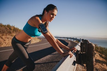 Young female athlete leaning on guardrail